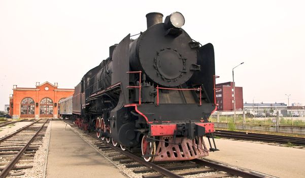 Steam locomotive beside a railway station platform. Retro train.