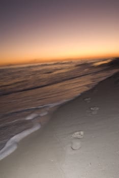 Footprints along the beach walking towards the setting sun