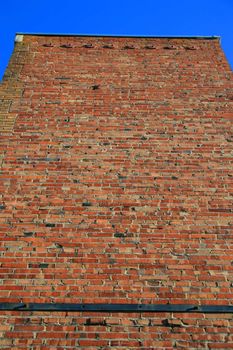 Brickwall over blue sky showing unique pattern.
