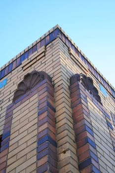 Corner of a brick building over blue sky.
