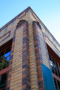 Corner of a brick building over blue sky.
