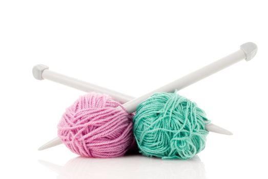 Balls of green and pink  knitting wool or yarn, with silver knitting needles.