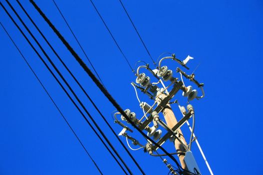 Close up of an electricity pole over blue sky.
