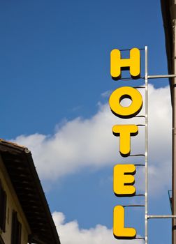 Yellow hotel sign over blue sky with some clouds