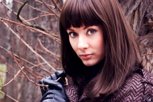 Stylish brunette with gloves and coat near thorns