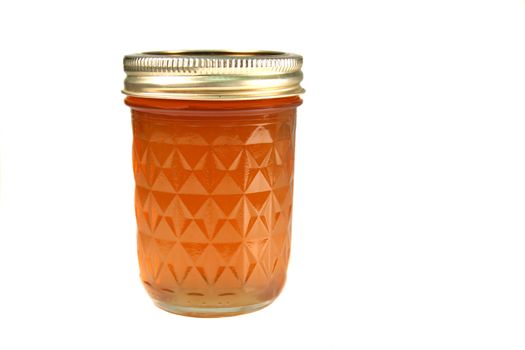 jar full of peach jelly over a white background