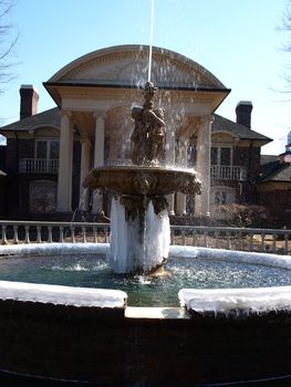A frozen fountain in front of a large house