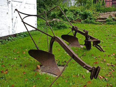Antique old rusty farm plow on the grass   