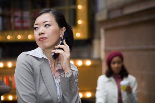 An attractive Asian business woman talking on her cell phone in the city.