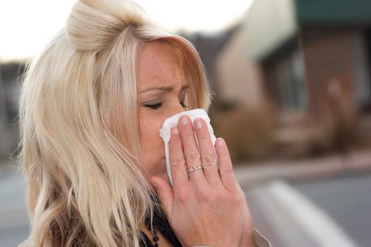 This young woman sneezing into a tissue either has a cold or really bad allergies.