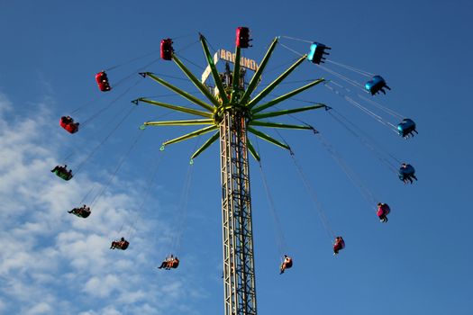 People flying in a turning ferris wheel in the blue sky