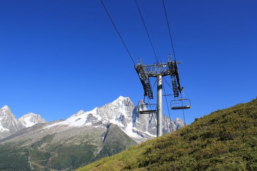 Chair lifts in the mountain in front of the Mont-Blanc massif, France