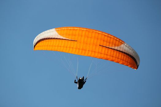 Red, white and black paraglider flying in a deep blue sky