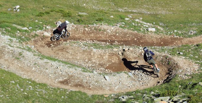 Two equipided bikers riding their VTT bike in the mountain