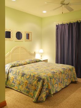 Green painted bedroom in a well apportioned beach house. Mirrors on the wall and a dark blue curtain decorates the room
