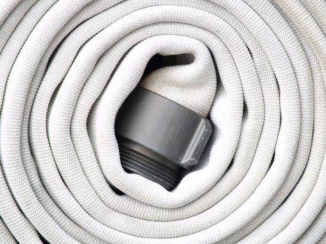 A white firehose coiled and ready to go in case of an emergency