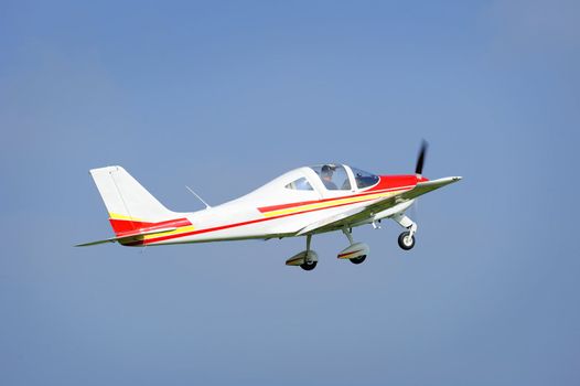 A light aircraft taking off into a clear blue sky.