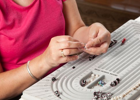 Close up of threading beads onto wire to make artistic bead necklace or bracelet