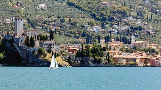 Sailing boat off the coast of Malcesine on Lake Garda with the castle framing the town