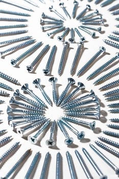 Picture made of screws different sizes on a white textile, metal and cloth.

