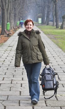 Happy girl with a backpack walking in an autumn park.