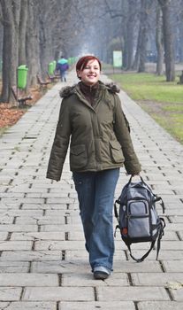 Happy girl with a backpack walking in an autumn park.