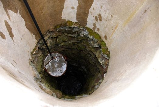 pulling out bucket full of drink water from deep well