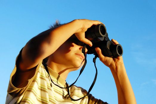 teen boy watching at black binoculars outdoor portrait