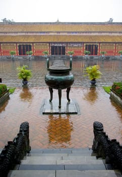 A view of a big tripod urn in the imperial city of Hue under the rain