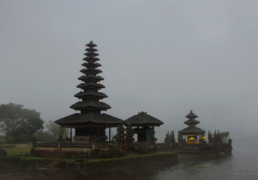 Temple with typical pointed roofs in Bali along the edge of a lake