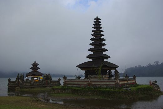 Temple with typical pointed roofs in Bali along the edge of a lake