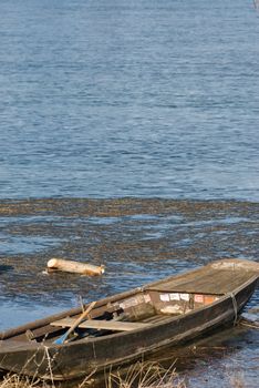 a boat which is frozen in the lake with a meditative beautiful mood in a romantic winter landscape