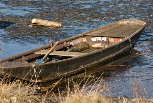 a boat which is frozen in the lake with a meditative beautiful mood in a romantic winter landscape