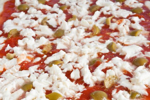 detail of raw pizza with tomato mozzarella and olives