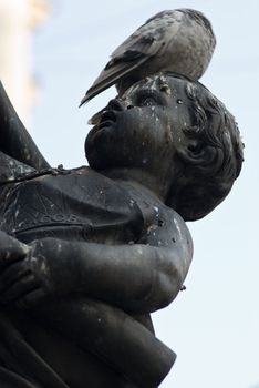 a statue of a child with a dove sitting on its head
