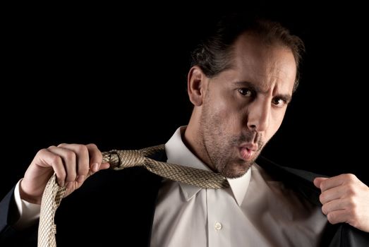 Adult businessman stressed pulling off tie on dark background