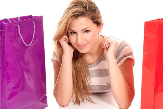 Young woman with shopping bags lying on floor on white background