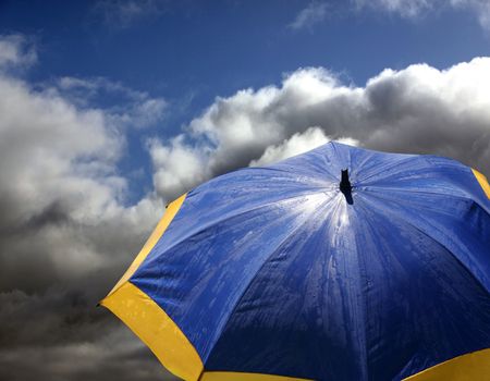 Blue - yellow beach umbrella on a background clouds
