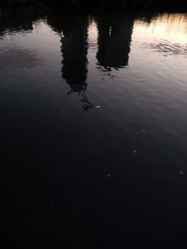 Distorted reflections of two buildings in some water.