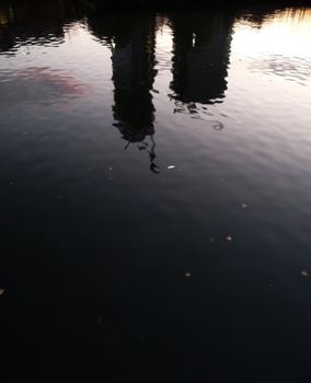 Distorted reflections of two buildings in some water.