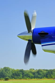 The propeller of an aircraft starting up, against a clear blue sky. Motion blur on the propeller blades.