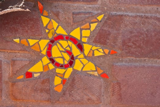 Yellow star mosaic with six and a half points on brick.