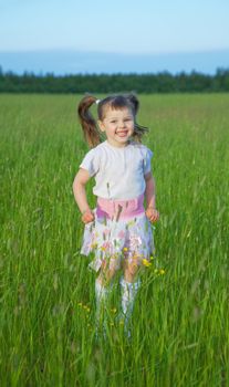 The happy child jumps on a green grass in the field