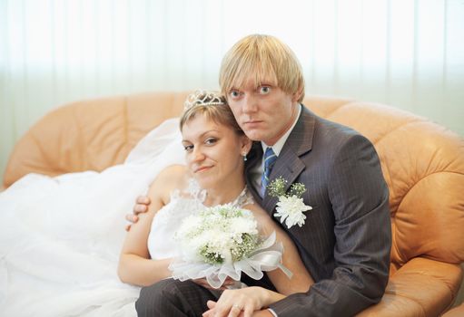 The future husband and the wife on a leather sofa in a solemn hall