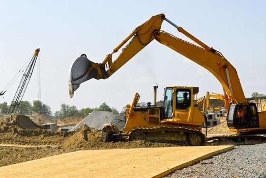 Yellow bulldozer machines digging and moving earth at construction site