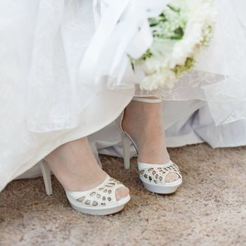 Shoes of the bride are visible from under a wedding dress