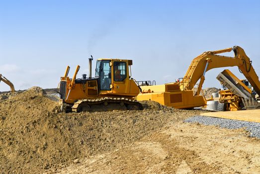 Yellow bulldozer machines digging and moving earth at construction site
