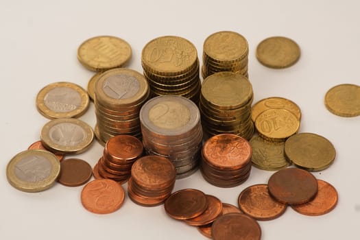 Piles and spread euro coins over white background