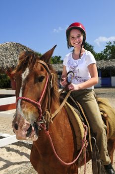 Young girl riding brown horse wearing helmet