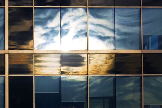Reflection of a cloudy sky in glass wall of an office building